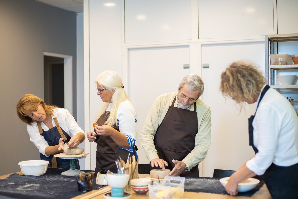 Des adultes réunis autour d’une table pour un atelier de poterie